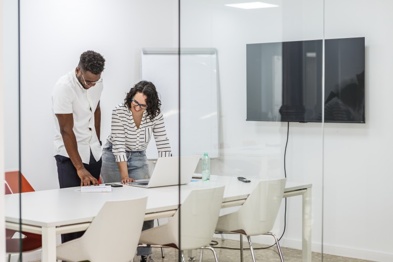 office meeting room with two people setting up technology